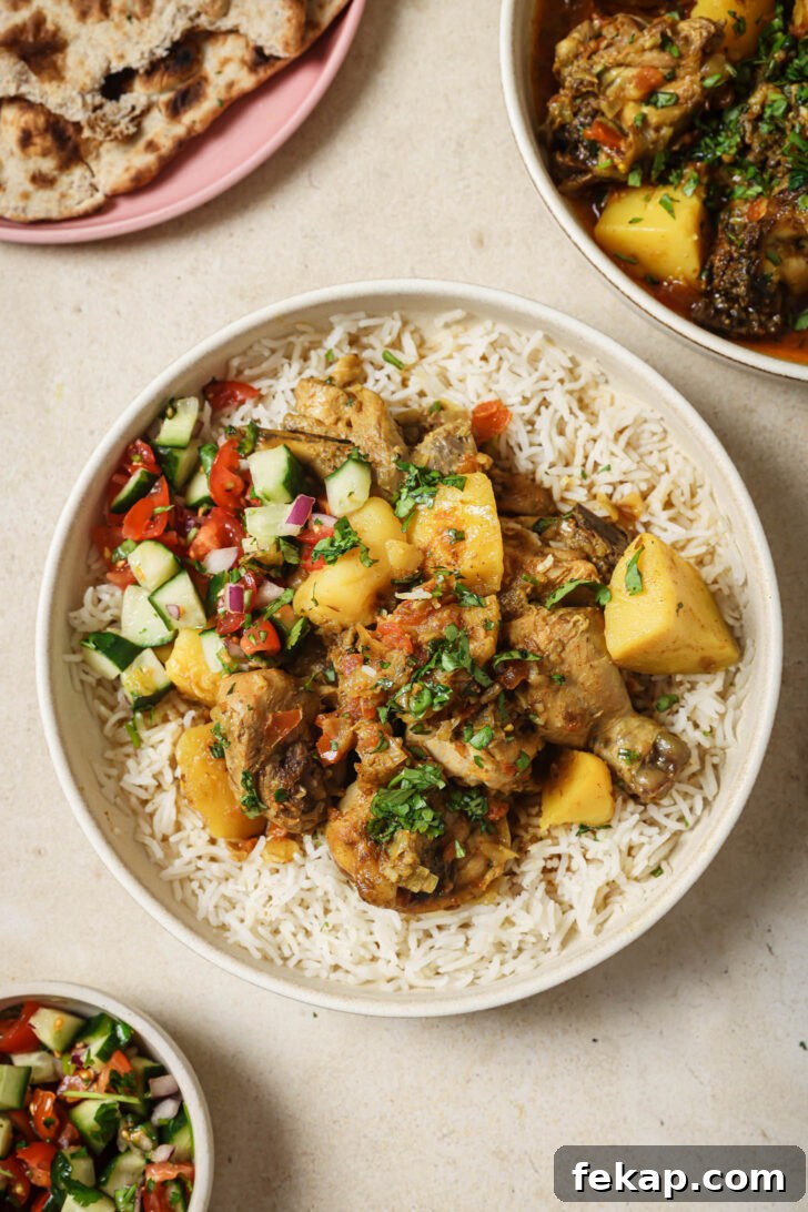 A bowl of rice topped with Pakistani Chicken Curry and Kachumber.