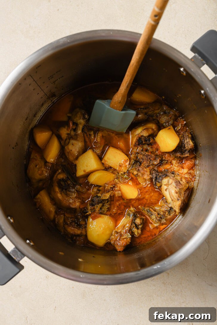 Pakistani Chicken Curry with Potatoes in an Instant Pot with a rubber spatula.