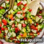 Close up of a big bowl of pickle de gallo with a corn chip sticking out.