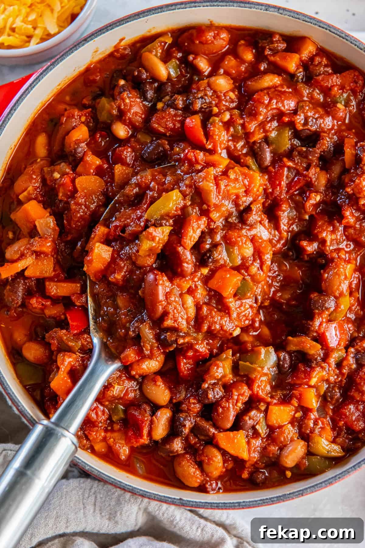 A large pot of three bean chili simmering on a white tabletop.