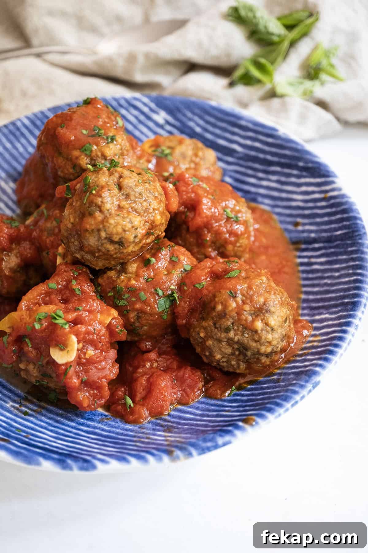 Crispy Italian Pan-Fried Meatballs Recipe 2 Meatballs covered in tomato sauce in a bowl.