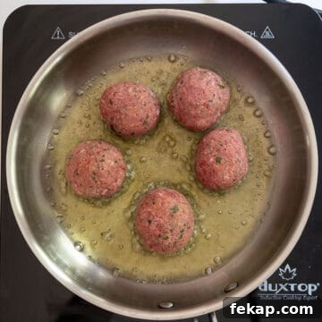 Crispy Italian Pan-Fried Meatballs Recipe 6 Frying raw meatballs in a saucepan.