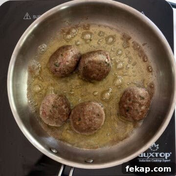 Crispy Italian Pan-Fried Meatballs Recipe 7 Meatballs browned while frying in a saucepan.