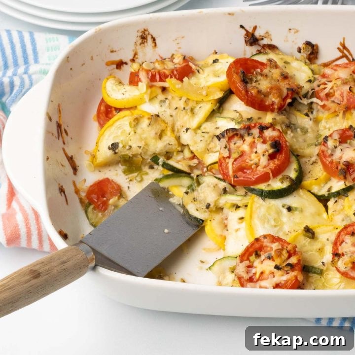 Baked layered casserole of yellow squash, zucchini, and tomatoes with herbs and cheese in a baking dish with a serving removed.