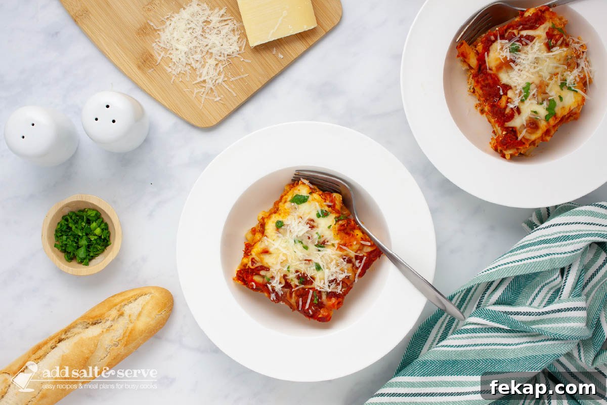 Bowl of cheesy meatless baked ziti garnished with fresh parsley and grated Parmesan cheese.