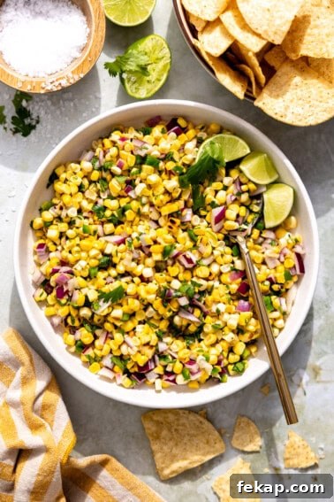 Bowl of roasted corn salsa with lime wedges.