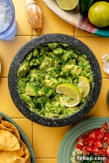 Molcajete with guacamole topped with lime wedges.
