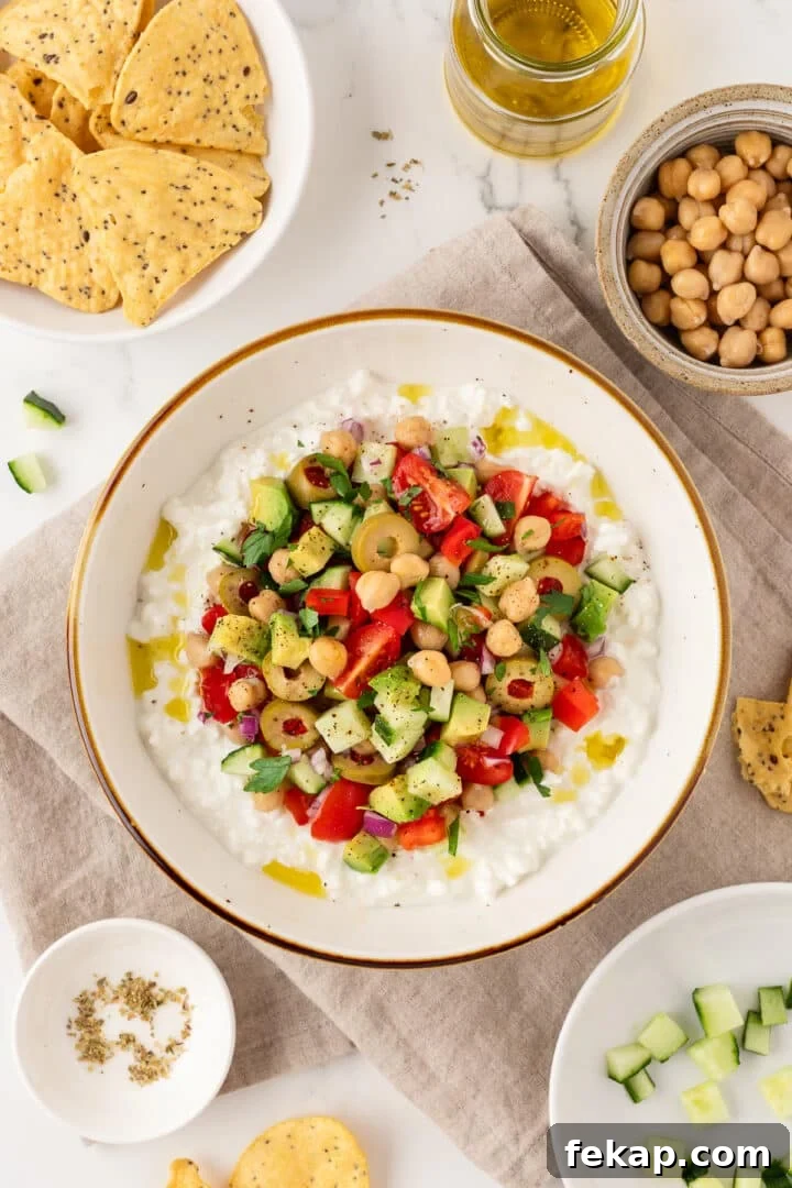 Greek-inspired cottage cheese salad in a bowl next to tortilla chips.