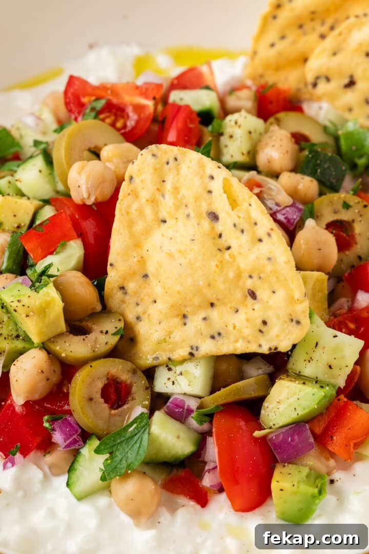 Cottage cheese greek salad in a bowl with a tortilla chip, read to scoop.