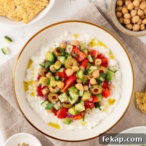 Greek-inspired cottage cheese salad in a bowl next to tortilla chips.