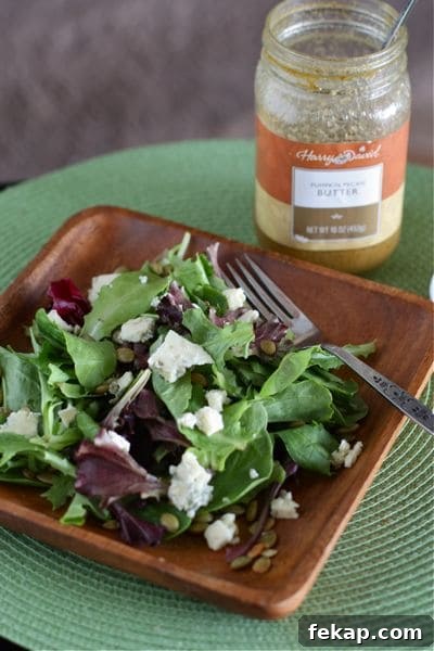 plate of mixed greens topped with pepitas and bleu cheese next to pumpkin butter vinaigrette