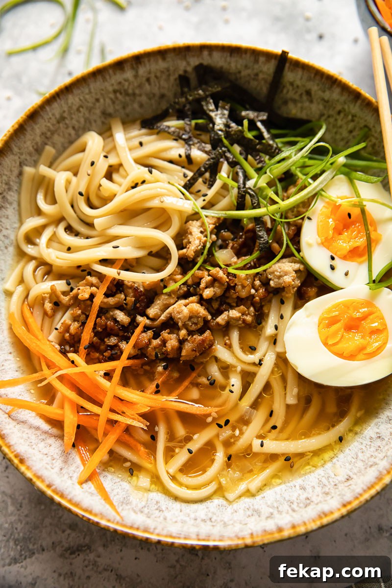 Japanese Udon Noodle Soup with Savory Broth 4 noodle soup topped with boiled egg, matchstick carrots and green onions