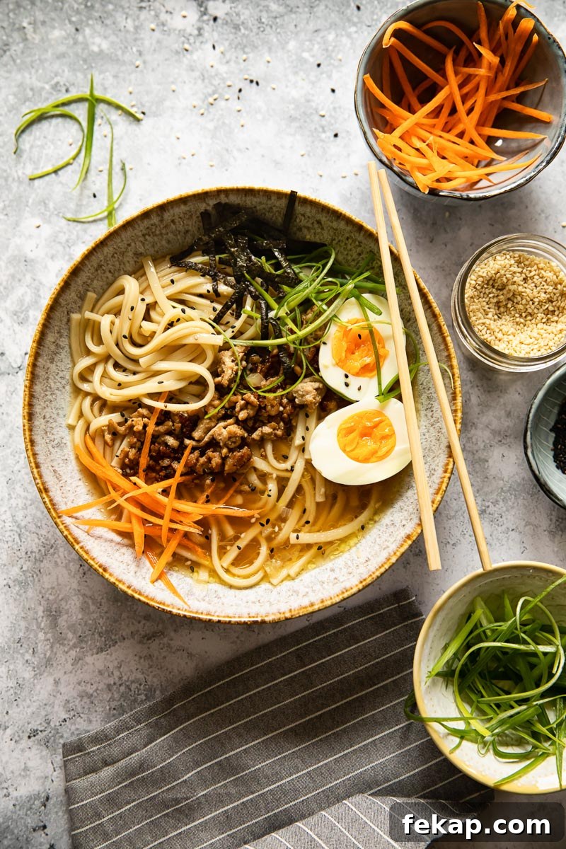 Japanese Udon Noodle Soup with Savory Broth 6 Japanese noodle soup in a bowl with various toppings around it in small bowls