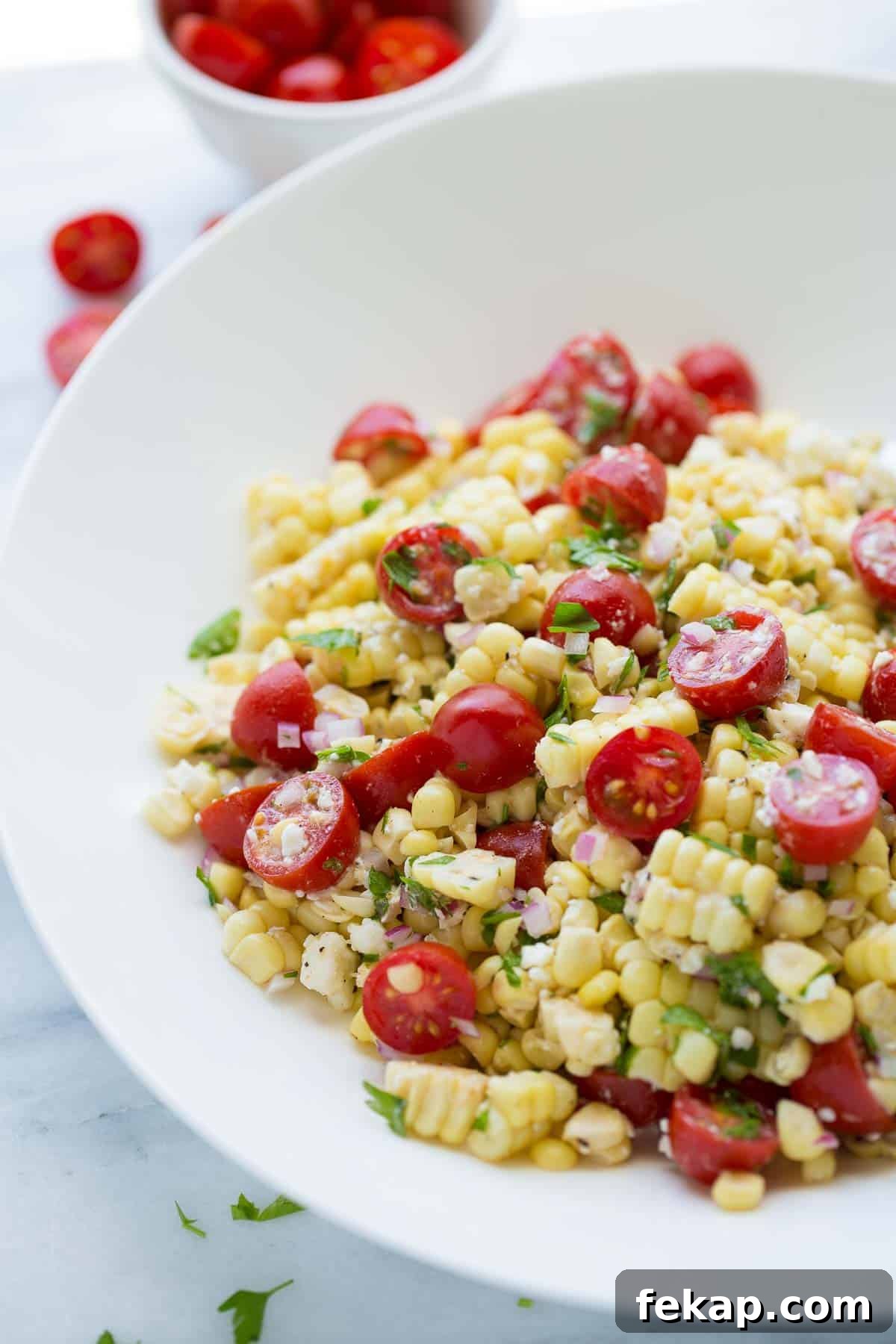 Summer Corn Salad shot of corn salad in white bowl topped with parsley