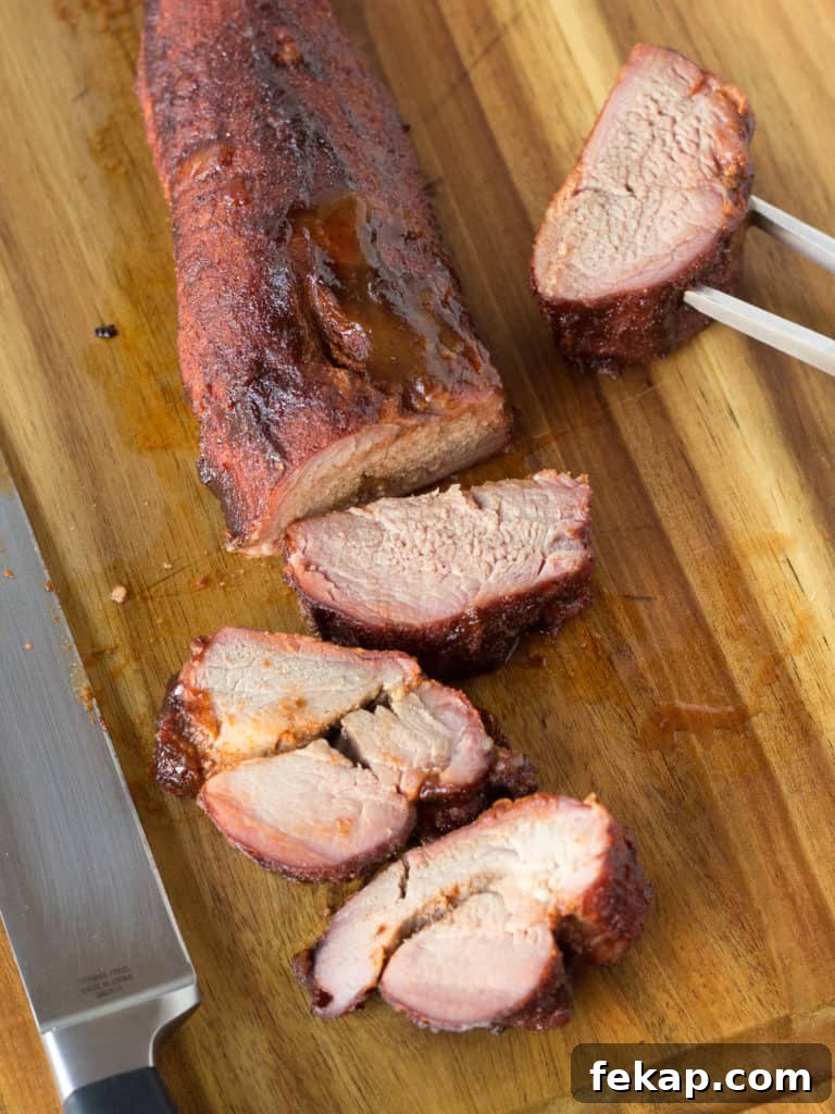 smoked pork tenderloin on a wood cutting board partially cut up into medallions