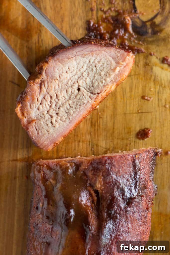 top down shot of a medallion of smoked pork with a meat fork sticking into it on a wood cutting board