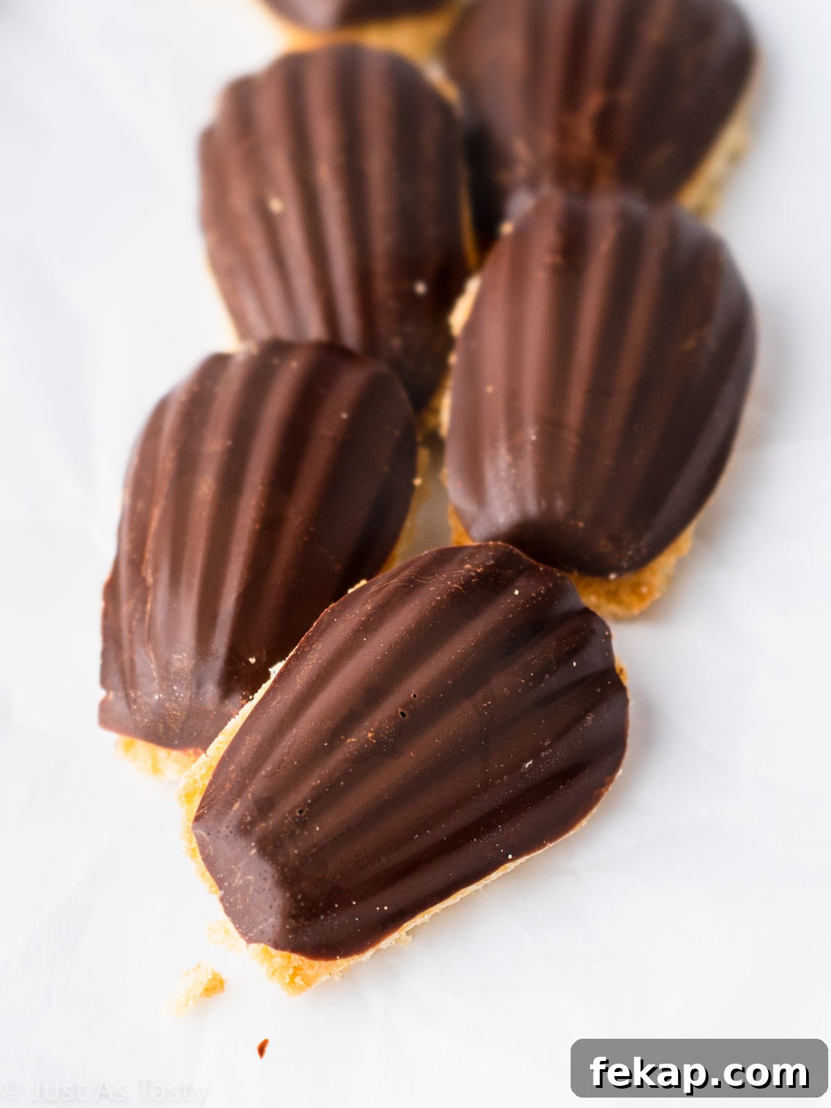 Gluten-Free Chocolate-Dipped Madeleines 2 Chocolate dipped madeleines on a white surface.