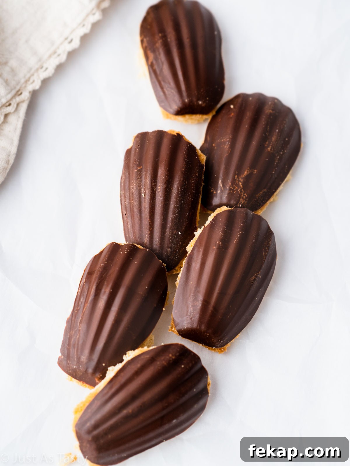 Gluten-Free Chocolate-Dipped Madeleines 9 Chocolate dipped madeleines on a white surface.