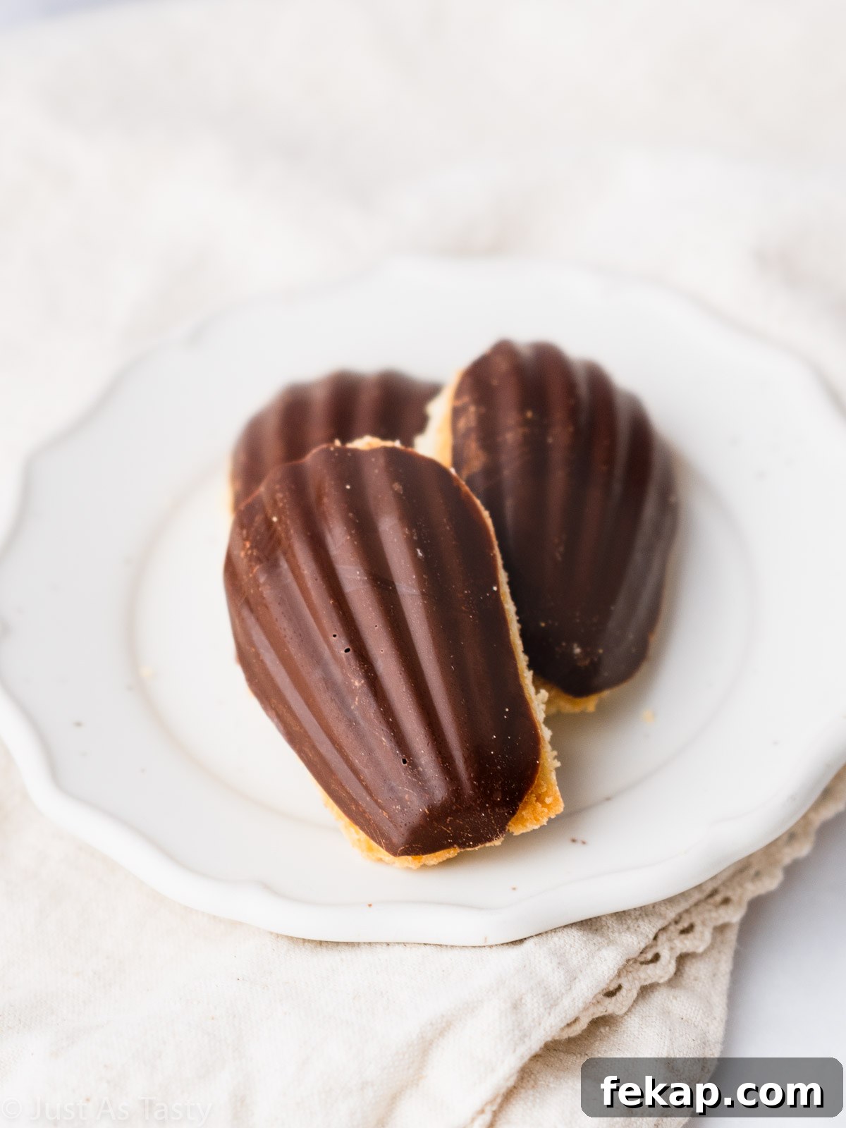 Gluten-Free Chocolate-Dipped Madeleines 10 Three chocolate dipped madeleines on a plate.