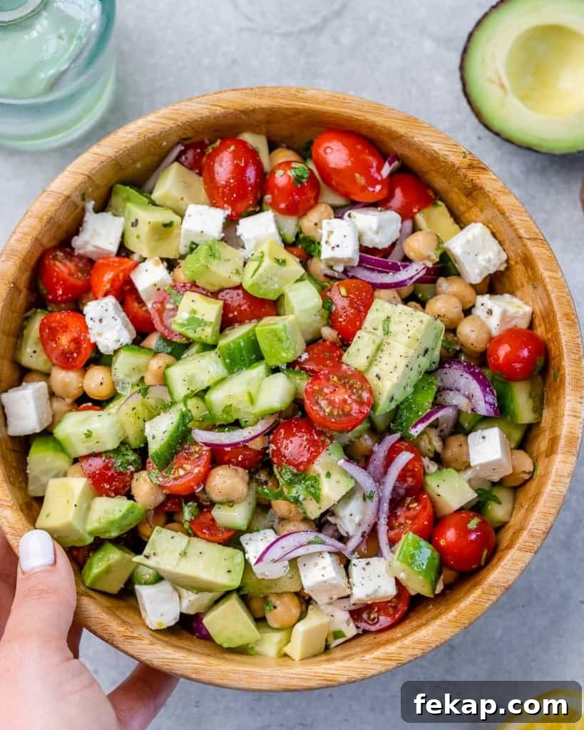 Chickpea and Feta Salad with Lemon Vinaigrette 2 hand holding brown bowl of greek chickpea feta salad