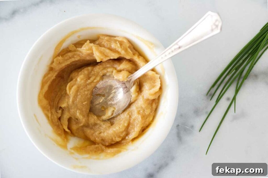 A dish with the miso and butter combined with a spoon. Fresh chives on the side.