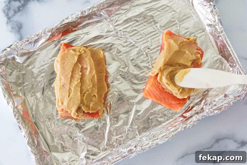 Spreading miso-butter on two portions of salmon.