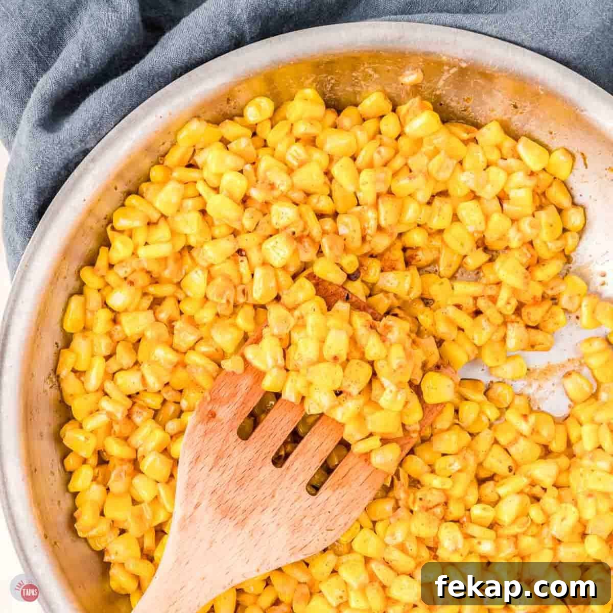Cajun Fried Corn Recipe: Spicy Southern Side Dish 13 silver skillet with yellow corn and a wood spoon