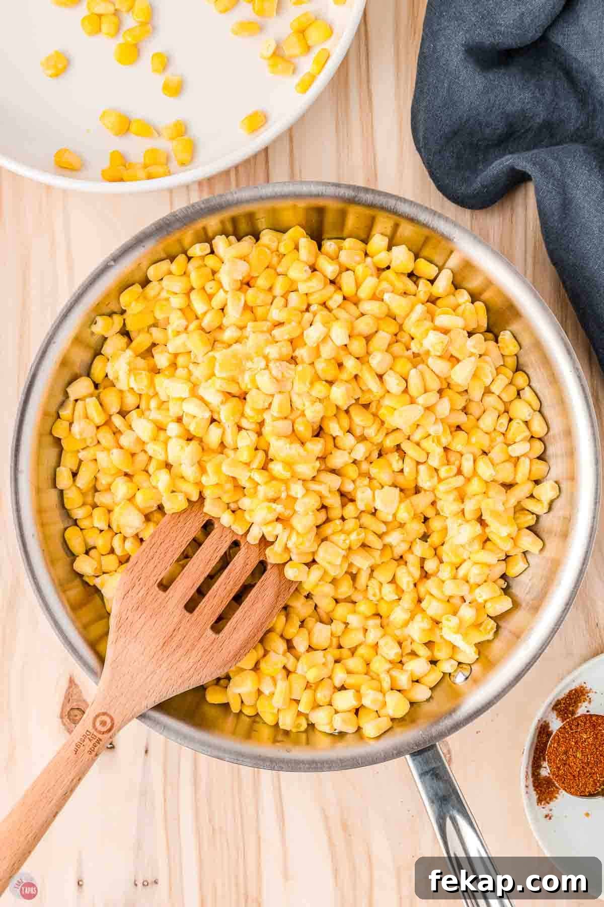 Cajun Fried Corn Recipe: Spicy Southern Side Dish 5 frozen corn kernels in a skillet with a slotted wood spatula