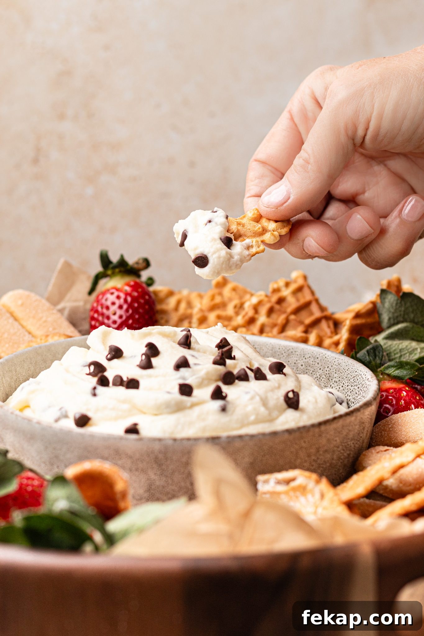 Creamy Ricotta Cannoli Dip with Chocolate Chips 3 a hand scooping out some cannoli dip with a broken waffle cone.