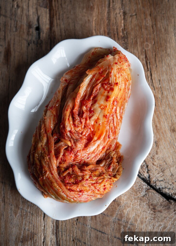 A head of fermented cabbage kimchi is on a white plate.