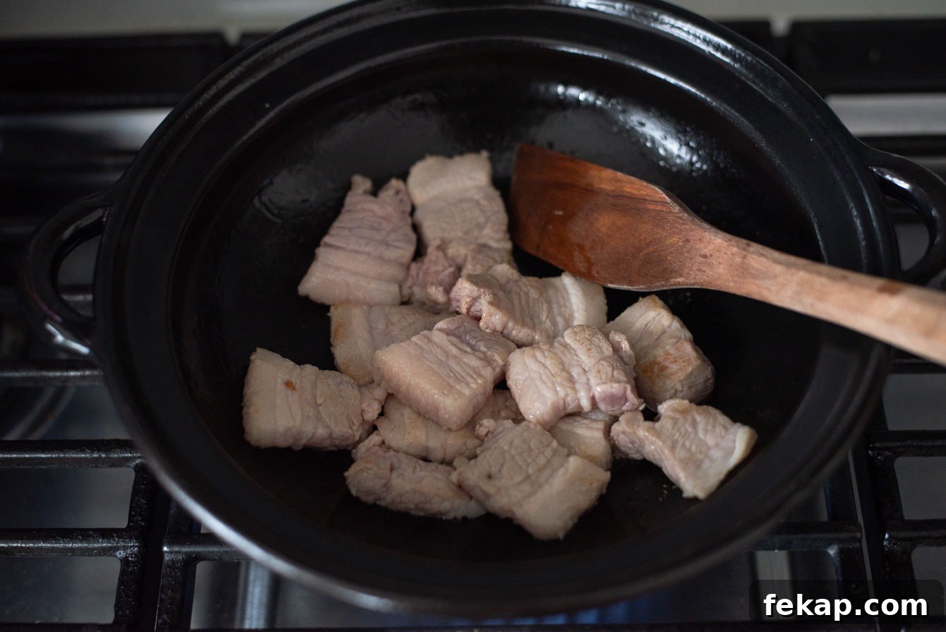 Pork belly slices browning in a pot for kimchi jjigae.