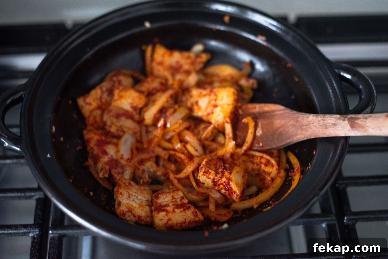 Pork belly and onions coated with Korean chili flakes (gochugaru) in a pot.