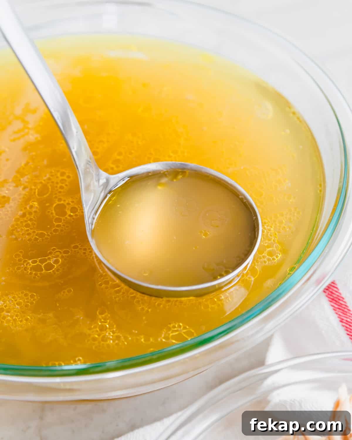 Broth Stock and Bone Broth Differences Explained 8 Bone broth in a glass bowl with a ladle.