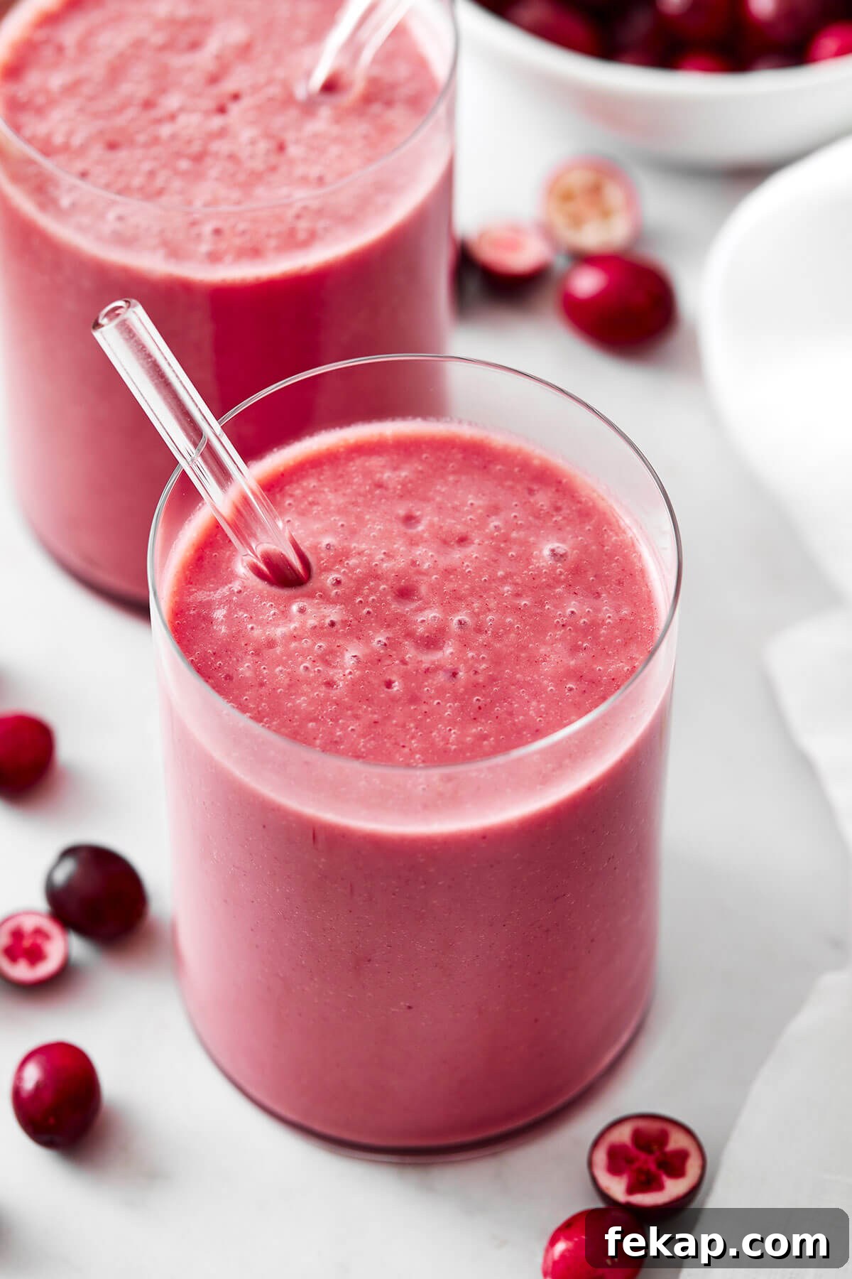 A glass of cranberry smoothie with a straw