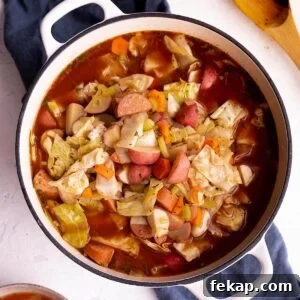 A white Dutch Oven with a soup sitting on a blue cloth napkin.