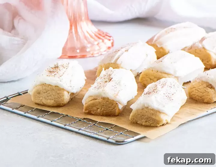 nutmeg cookies on a wire rack with a pink cake stand and dish towel behind them