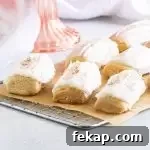 nutmeg cookies on a wire rack with a pink cake stand and dish towel behind them