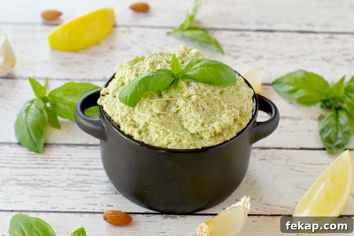 Almond Basil Pesto Recipe 2 basil pesto with almond in a black dish with almonds, basil, garlic and lemon surrounding the dish