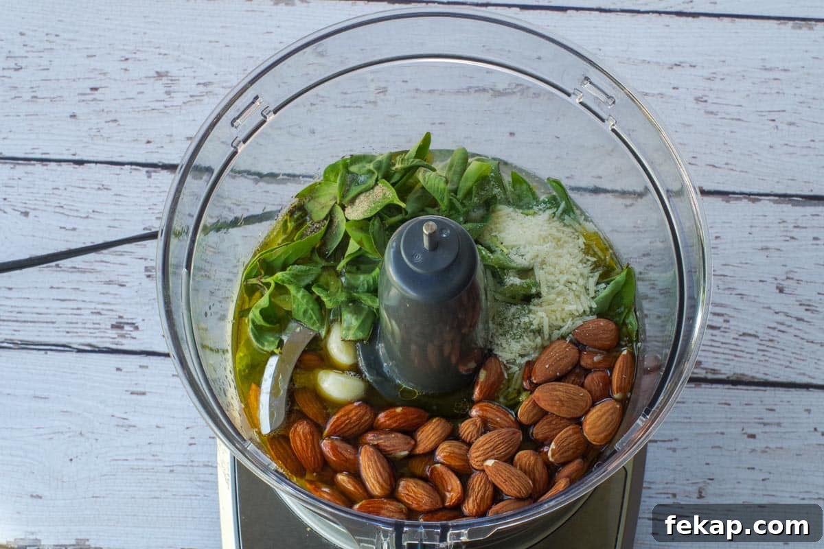 Almond Basil Pesto Recipe 6 All ingredients for almond basil pesto in the bowl of a food processor.