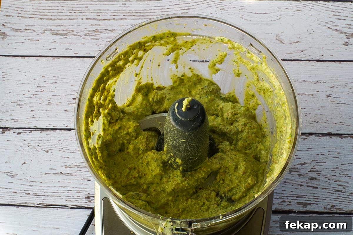 Almond Basil Pesto Recipe 7 Basil pesto blended in bowl of food processor.