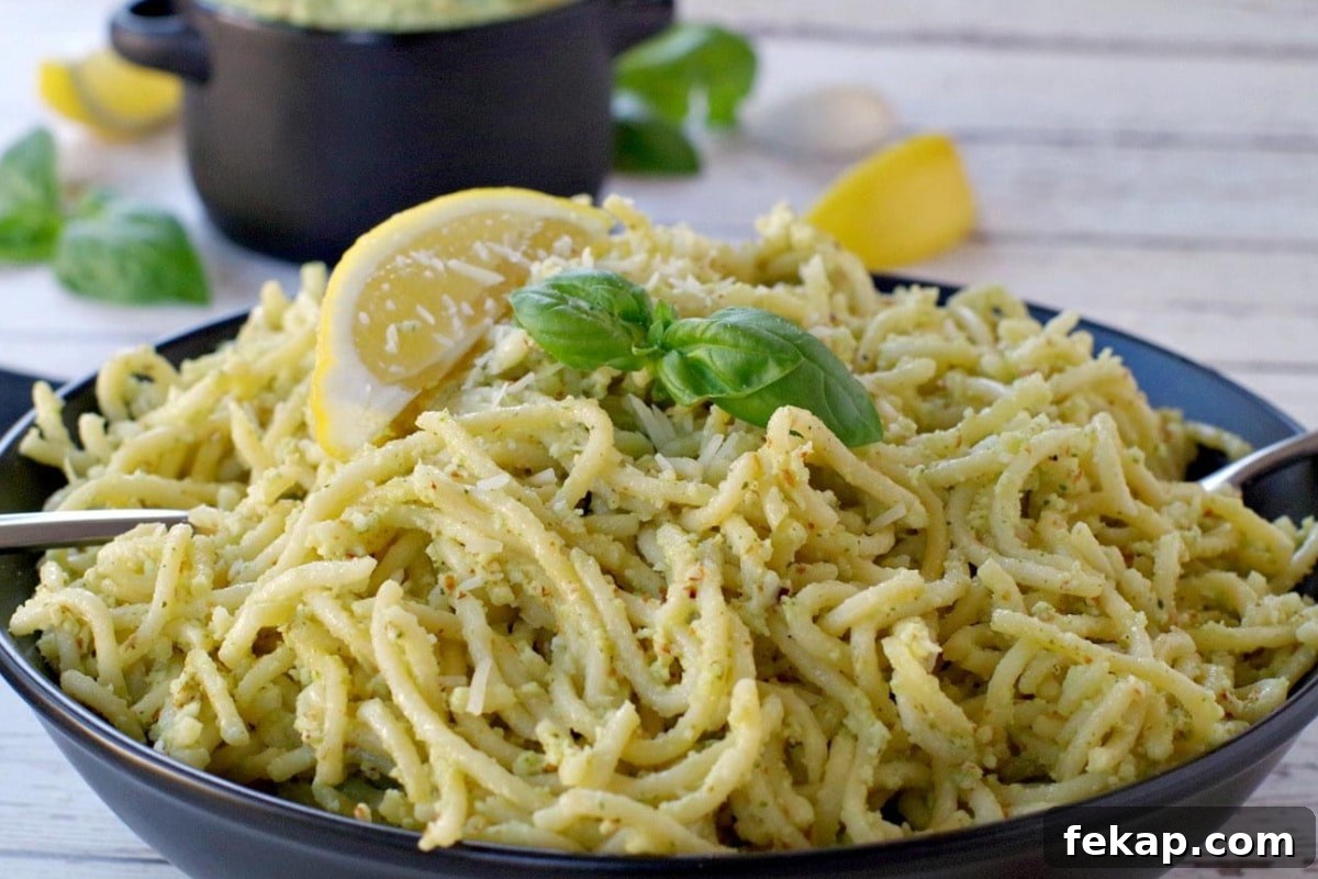 Almond Basil Pesto Recipe 8 pesto on spaghetti noodles with more pesto (in black container in background)