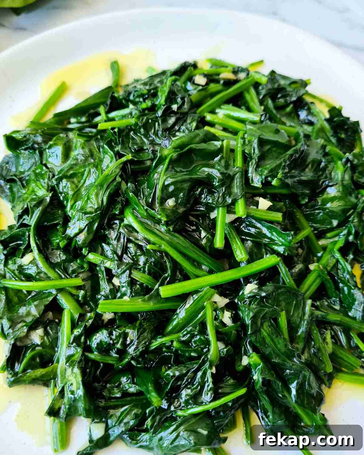 Garlic Stir-Fried Spinach Recipe 2 Close up of glossy sauteed spinach on a plate