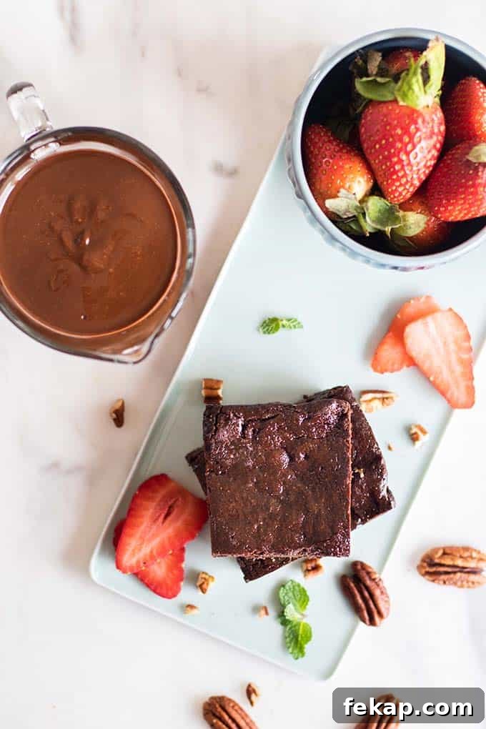 Brownies stacked on a blue plate with a bowl of strawberries next to it.