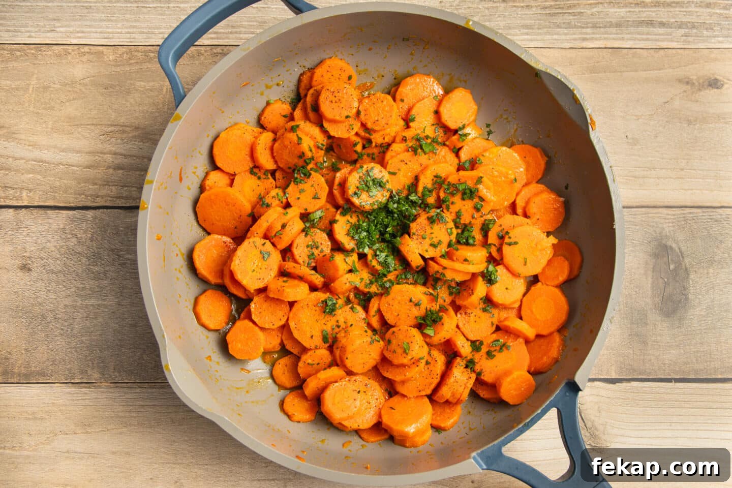 Butter-Glazed French Vichy Carrots Recipe 6 This is a picture of sliced carrots cooking in a skillet with added parsley.