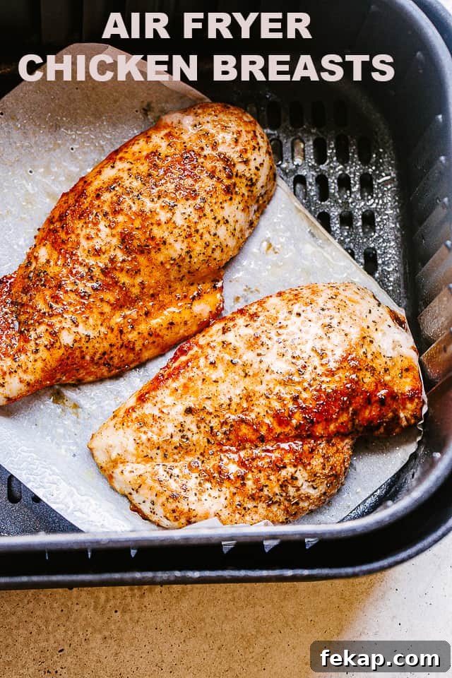 Cooked chicken breasts in the basket of an air fryer.
