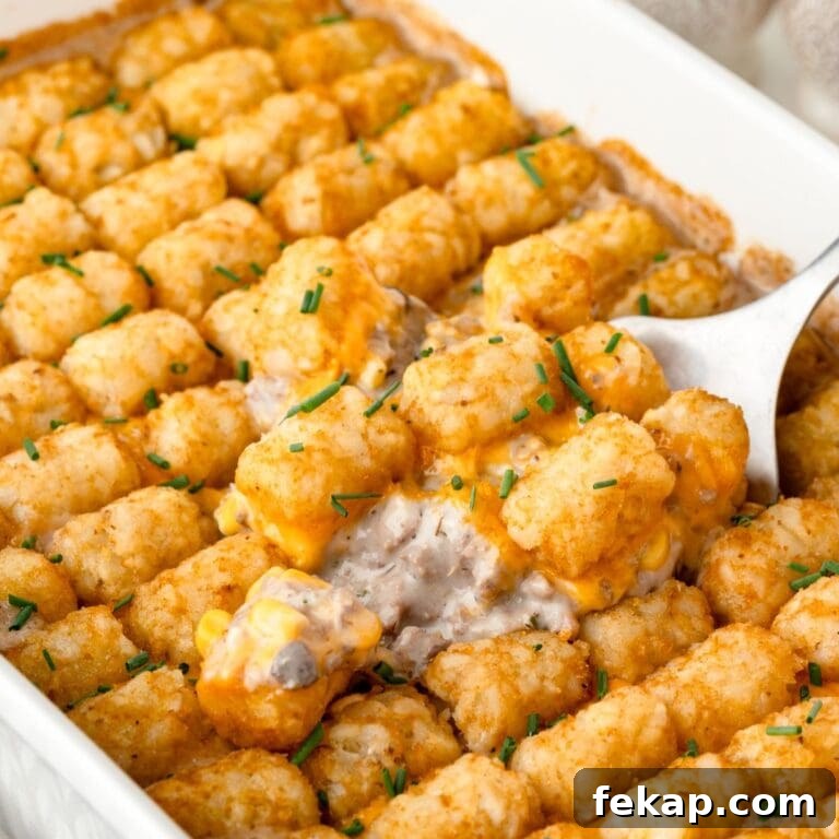 A baking dish filled with Hamburger Tater Tot Casserole lifted up with a large spoon.