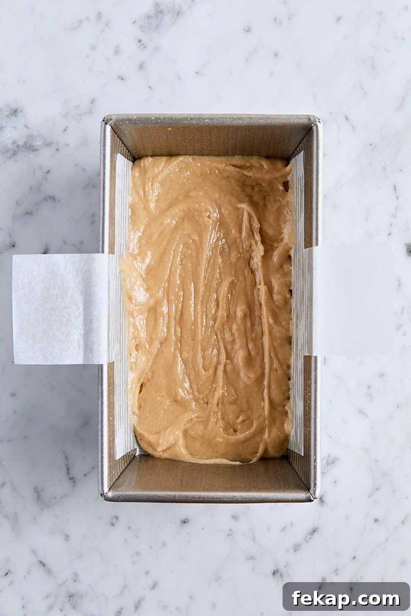 Half of the apple bread batter in parchment-lined loaf pan