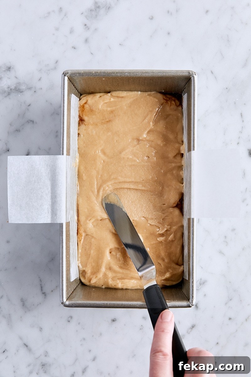 Spreading apple fritter bread batter over the chopped apple layer with an offset spatula