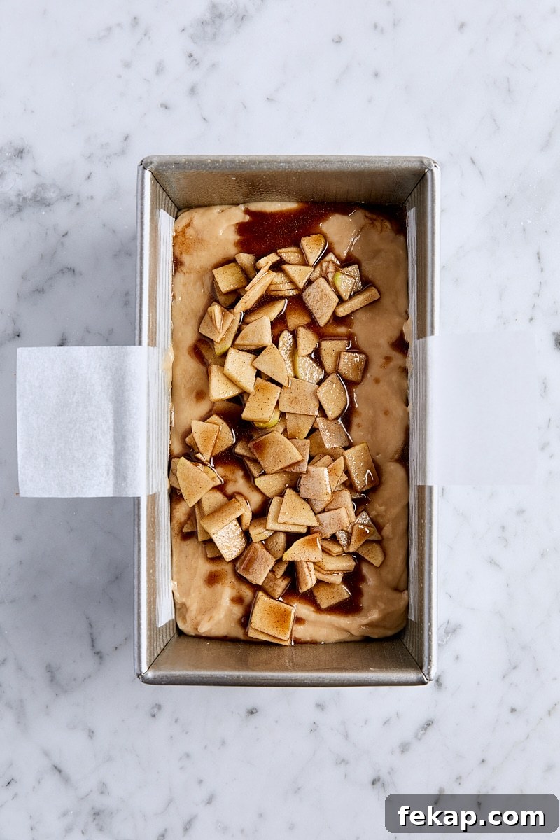 Assembled apple fritter bread in parchment-lined loaf pan