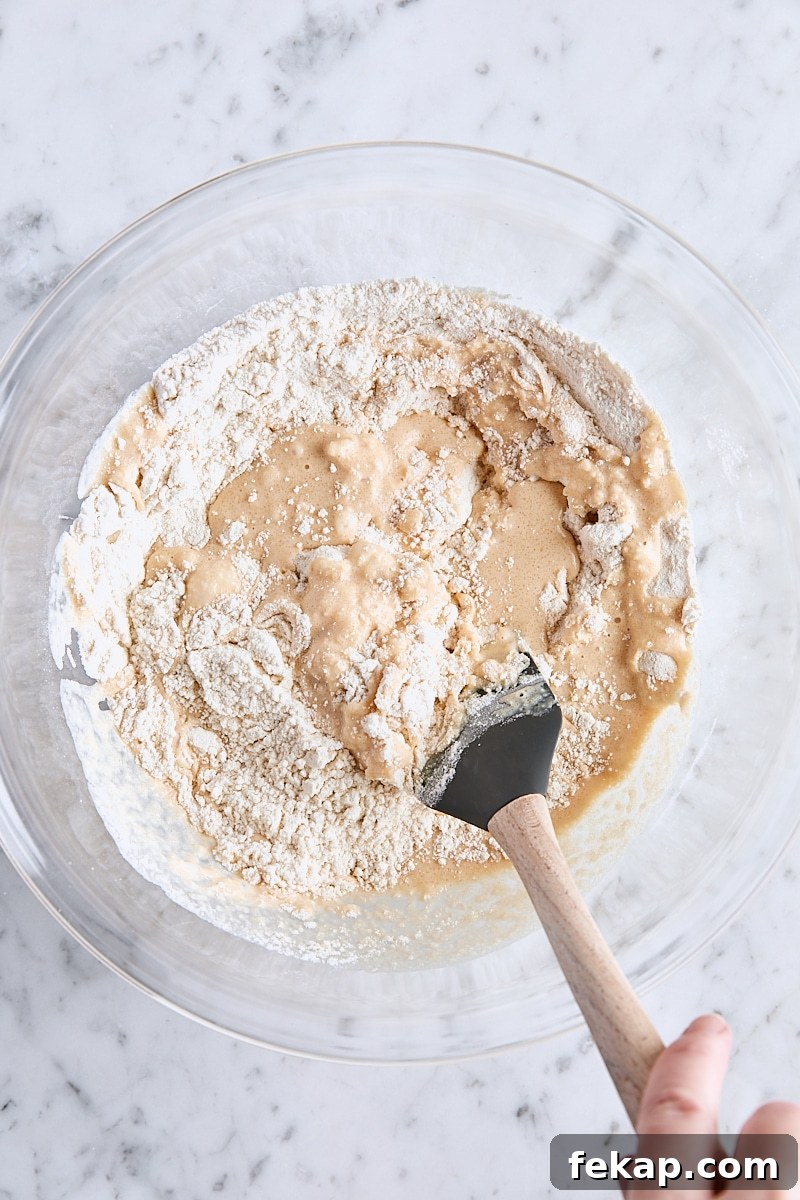 Folding apple cider mixture into flour mixture with a rubber spatula